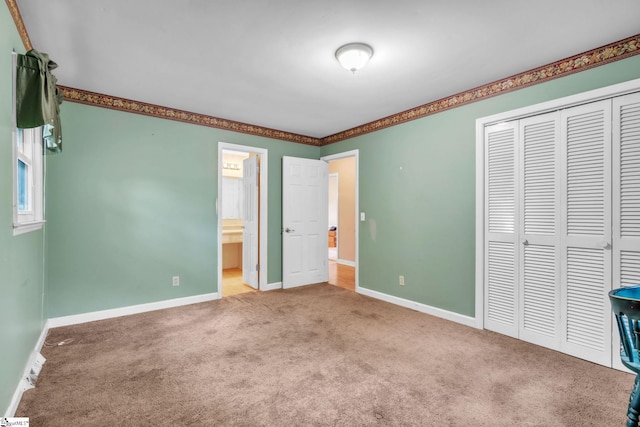 unfurnished bedroom with ensuite bath, a closet, baseboards, and carpet floors