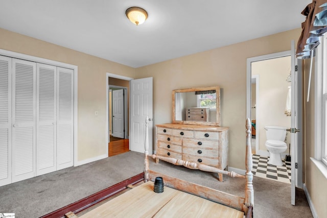 carpeted bedroom featuring a closet, connected bathroom, and baseboards