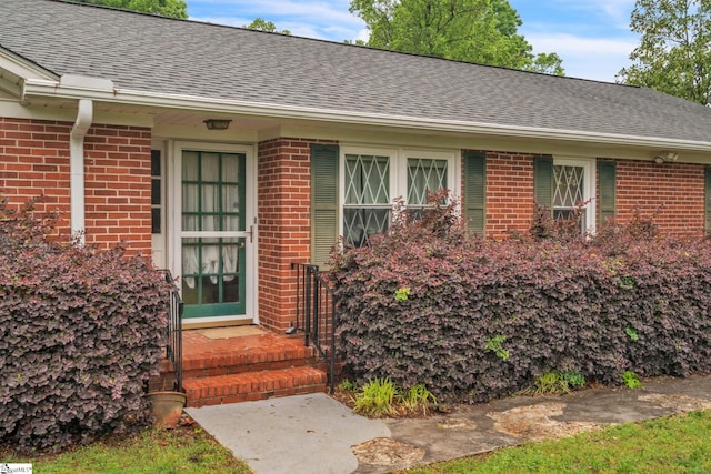 property entrance with roof with shingles and brick siding