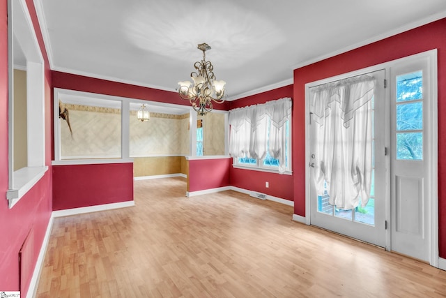 interior space with ornamental molding, wood finished floors, a chandelier, and baseboards