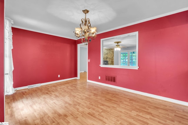empty room with ornamental molding, visible vents, wood finished floors, and baseboards