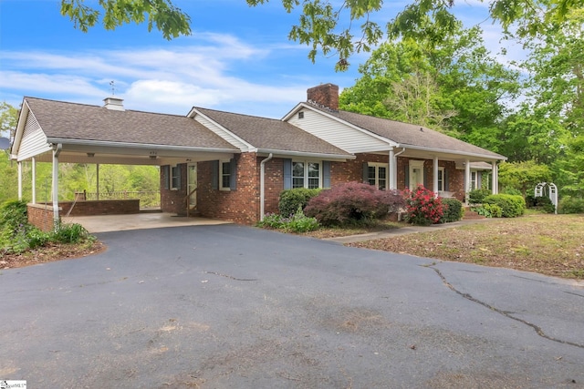 single story home featuring driveway, a carport, a chimney, roof with shingles, and brick siding