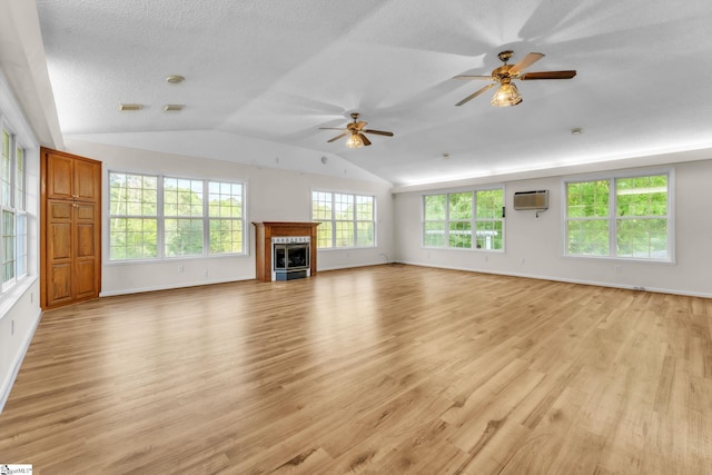 unfurnished living room with a glass covered fireplace, light wood finished floors, an AC wall unit, a ceiling fan, and lofted ceiling