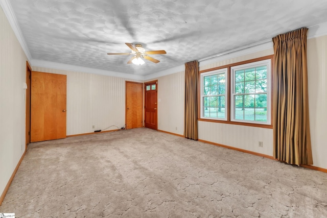 empty room featuring baseboards, ceiling fan, carpet floors, and crown molding