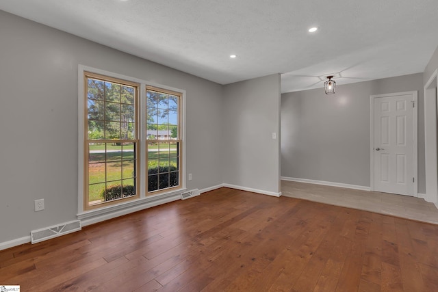 spare room featuring baseboards, visible vents, and hardwood / wood-style flooring