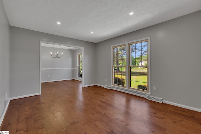 empty room featuring dark wood finished floors, visible vents, and an inviting chandelier