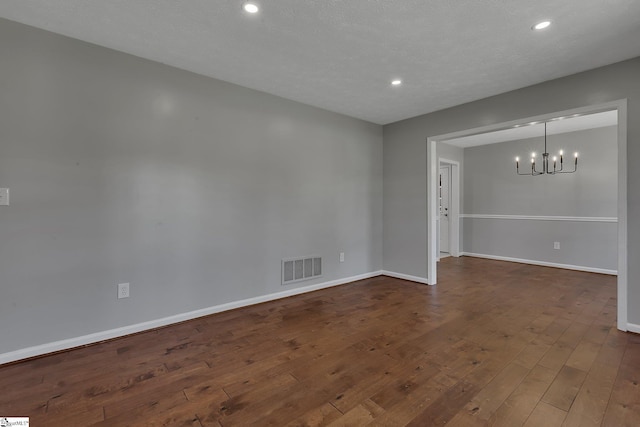 unfurnished room featuring baseboards, visible vents, a notable chandelier, and dark wood-style floors