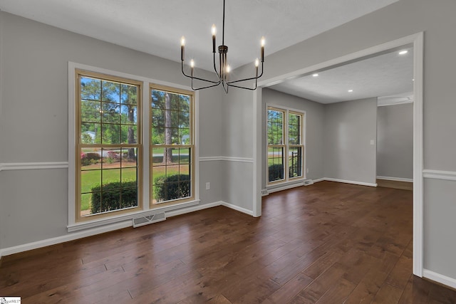 unfurnished dining area with dark wood-style floors, an inviting chandelier, visible vents, and baseboards