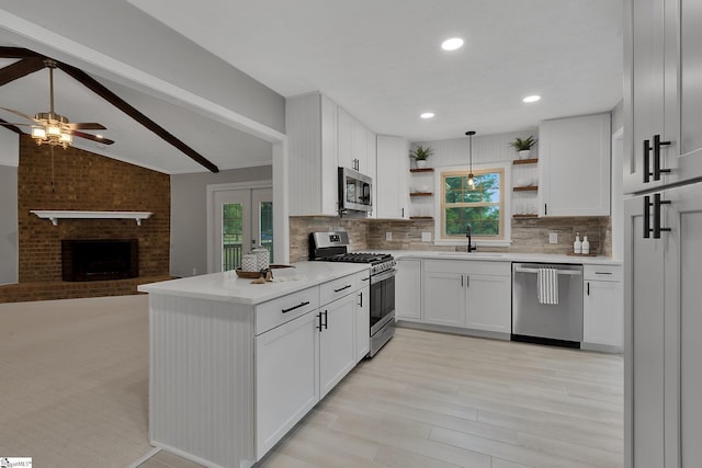 kitchen with open shelves, plenty of natural light, appliances with stainless steel finishes, and a sink