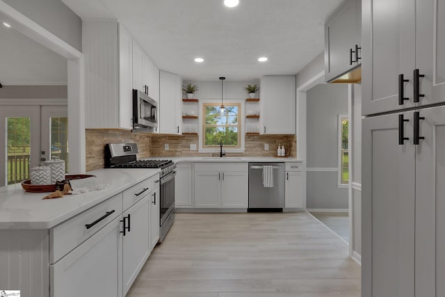 kitchen with tasteful backsplash, open shelves, appliances with stainless steel finishes, light wood-type flooring, and recessed lighting