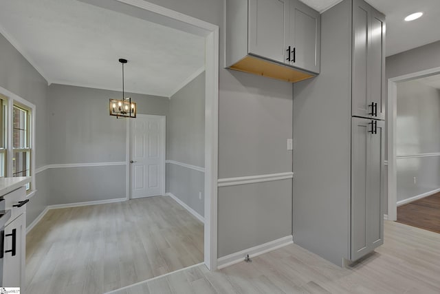 interior space with gray cabinets, baseboards, a chandelier, and light wood-style floors