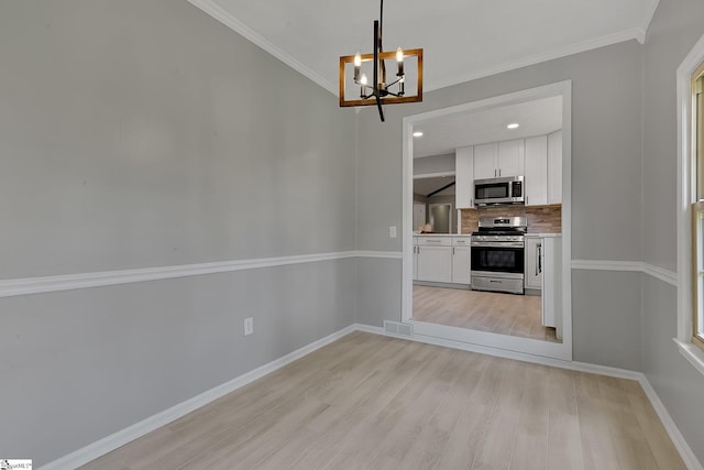 unfurnished dining area featuring crown molding, light wood-style flooring, visible vents, baseboards, and a notable chandelier