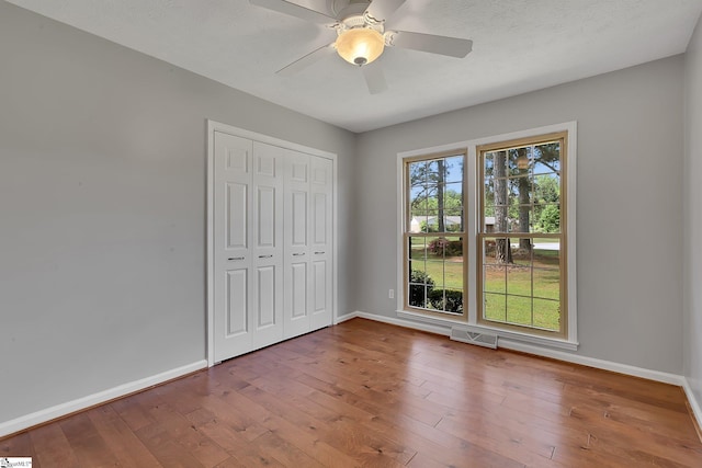 unfurnished bedroom featuring visible vents, hardwood / wood-style floors, and baseboards