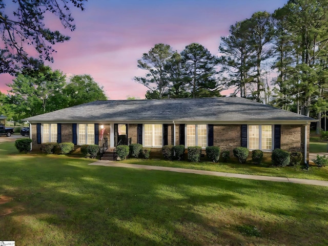 ranch-style home with brick siding and a yard