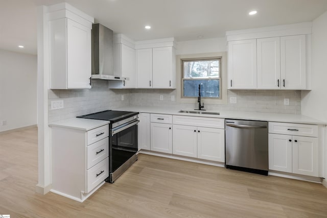kitchen featuring tasteful backsplash, a sink, stainless steel appliances, light countertops, and wall chimney exhaust hood