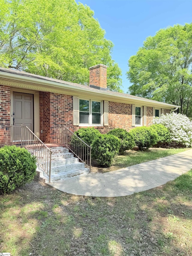 view of front of house featuring a chimney and brick siding