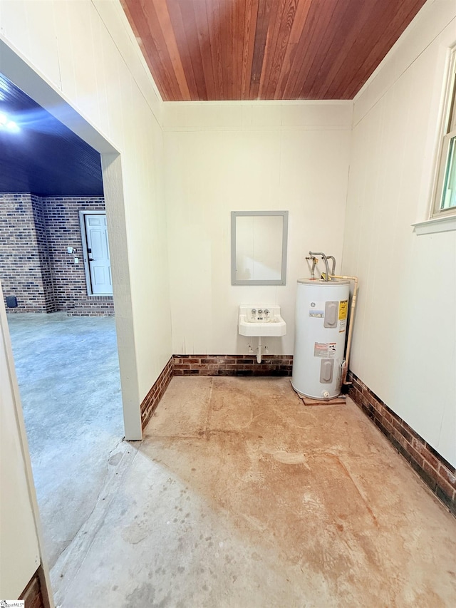 laundry room featuring wood ceiling, brick wall, electric water heater, and a sink