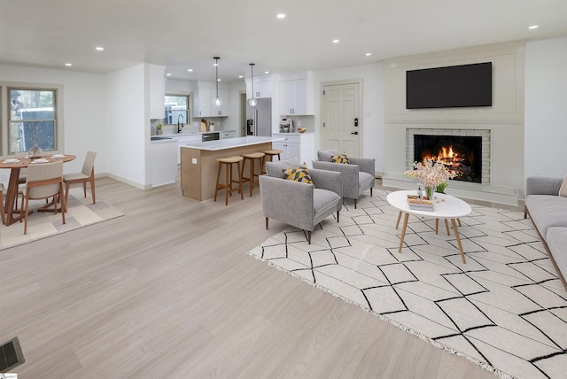 living area with visible vents, recessed lighting, light wood-style flooring, and a brick fireplace