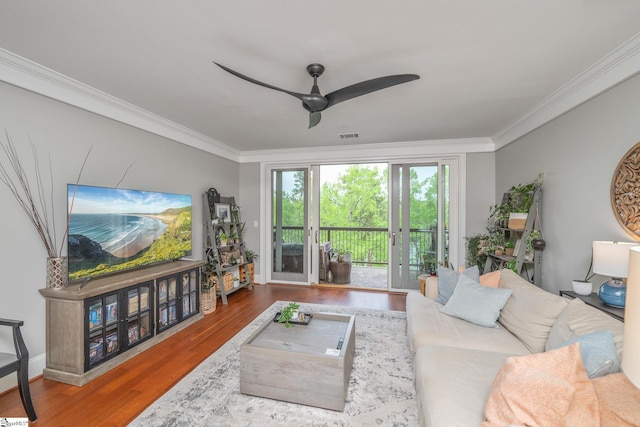 living area featuring wood finished floors, crown molding, visible vents, and a ceiling fan
