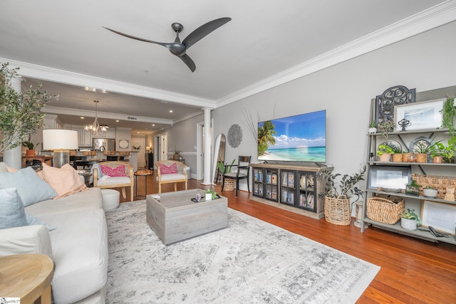 living area with wood finished floors, recessed lighting, ornamental molding, and ceiling fan with notable chandelier