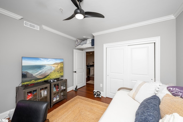 living area featuring wood finished floors, baseboards, visible vents, a ceiling fan, and crown molding