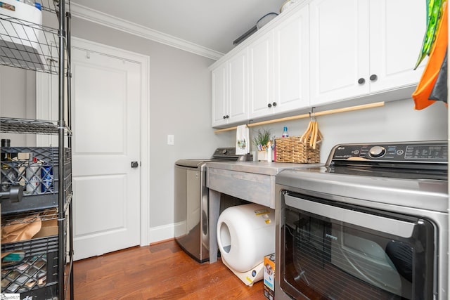 laundry area featuring cabinet space, dark wood-type flooring, baseboards, ornamental molding, and washer and dryer