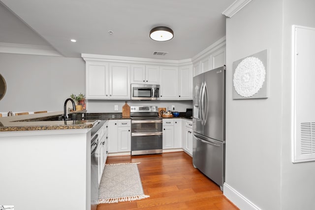 kitchen featuring a peninsula, visible vents, white cabinetry, and stainless steel appliances