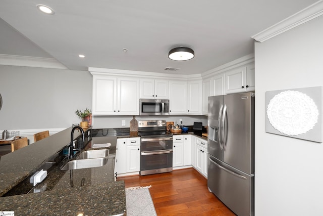 kitchen with crown molding, white cabinets, a sink, appliances with stainless steel finishes, and visible vents
