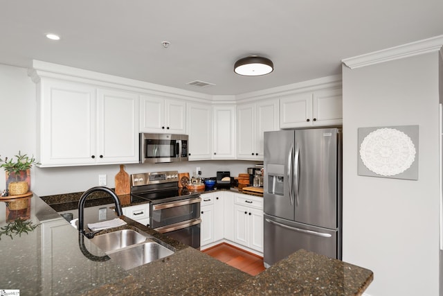 kitchen with visible vents, stainless steel appliances, white cabinets, and a sink