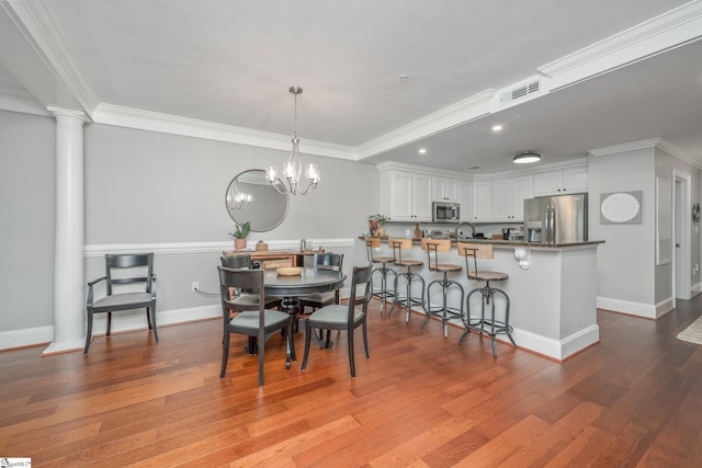 dining room with ornamental molding, visible vents, wood finished floors, and baseboards