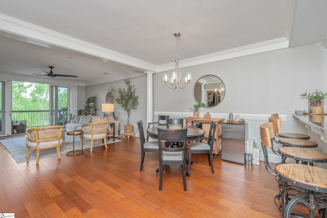 dining room featuring wood finished floors, crown molding, and ceiling fan with notable chandelier