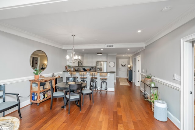 dining area featuring crown molding, visible vents, light wood-style floors, baseboards, and a notable chandelier