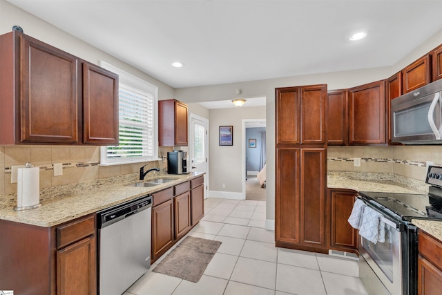 kitchen with light stone counters, light tile patterned floors, appliances with stainless steel finishes, backsplash, and a sink