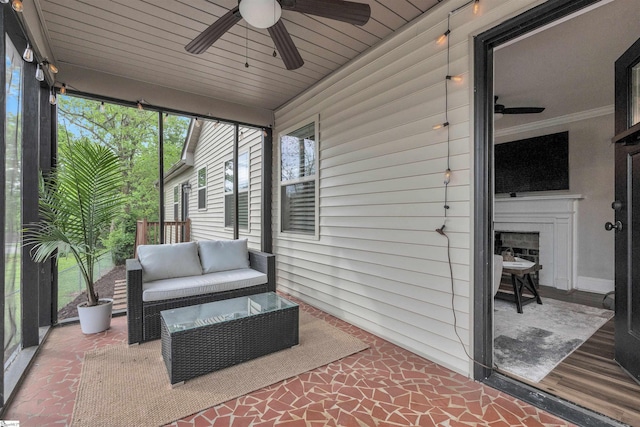 sunroom featuring a wealth of natural light, ceiling fan, and an outdoor living space with a fireplace