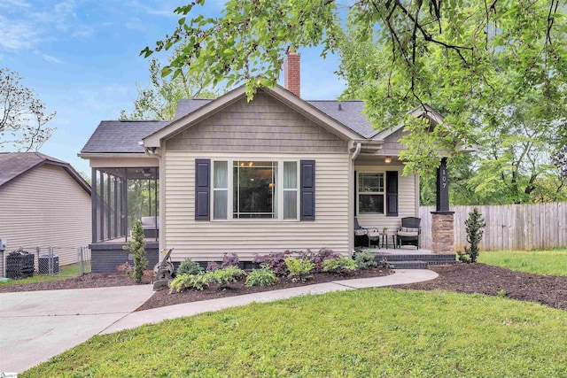 bungalow featuring a chimney, fence, a front lawn, and a sunroom