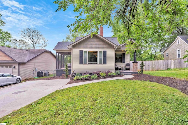 bungalow-style house featuring a chimney, a front yard, fence, a porch, and a sunroom