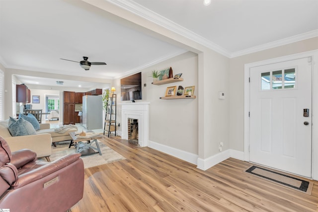 living room featuring a wealth of natural light, ornamental molding, and light wood-style flooring