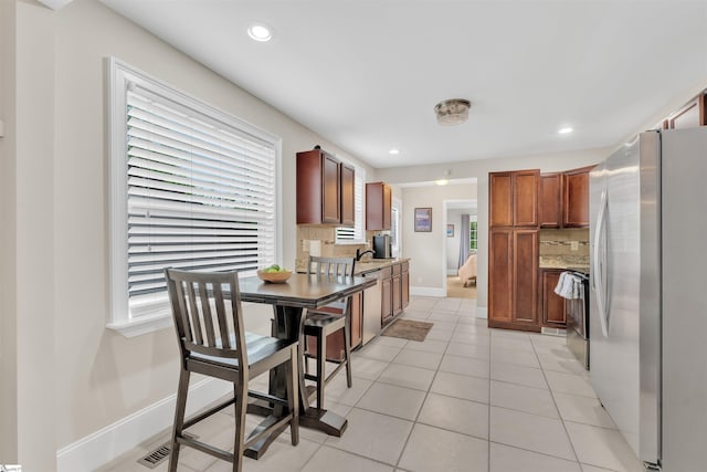 kitchen with tasteful backsplash, recessed lighting, stainless steel appliances, light tile patterned floors, and baseboards