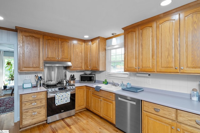 kitchen featuring stainless steel appliances, backsplash, under cabinet range hood, and a sink