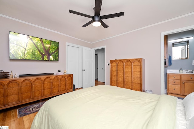 bedroom featuring crown molding, ceiling fan, wood finished floors, and ensuite bath