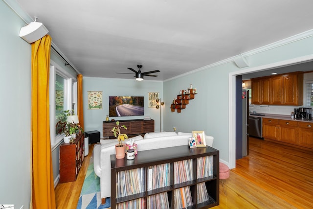 living area with ornamental molding, a ceiling fan, baseboards, and light wood-type flooring