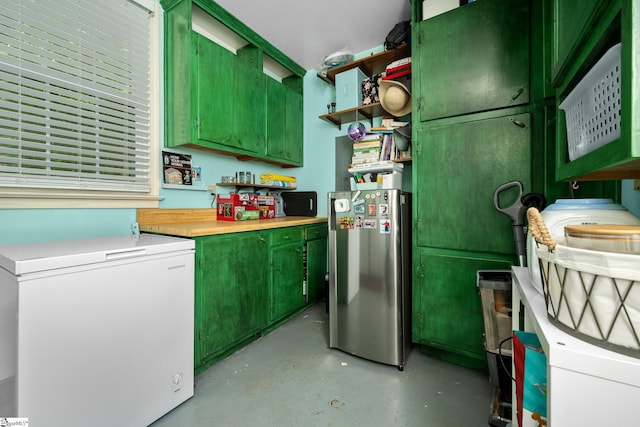kitchen featuring freestanding refrigerator, green cabinetry, open shelves, white refrigerator, and finished concrete floors