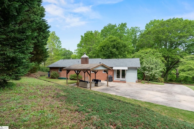 exterior space with a patio, a yard, a chimney, and brick siding