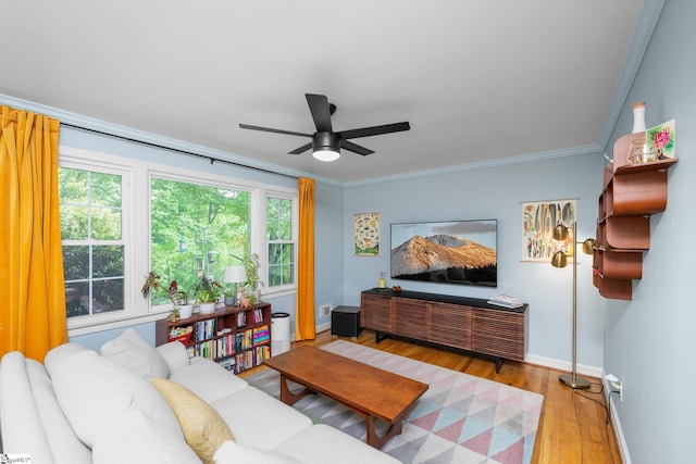 living area with crown molding, light wood finished floors, ceiling fan, and baseboards