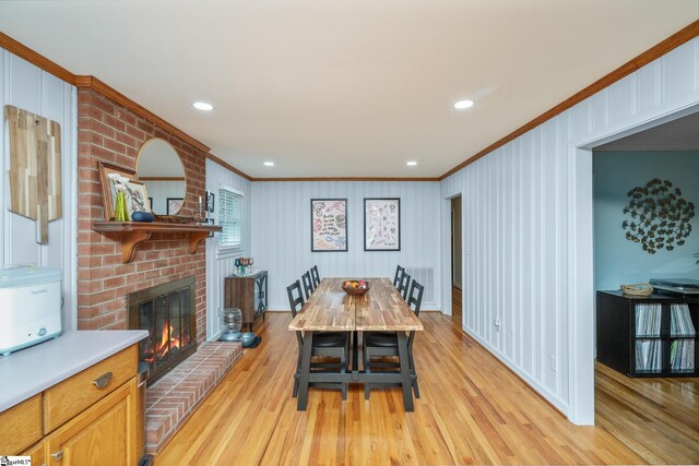 dining space featuring recessed lighting, light wood finished floors, a brick fireplace, baseboards, and crown molding