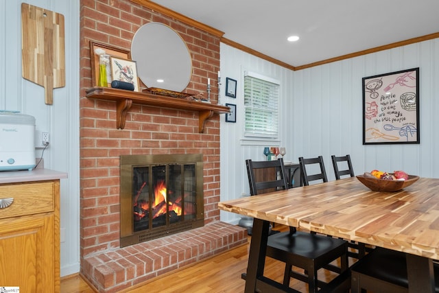 dining space with crown molding, a brick fireplace, and wood finished floors