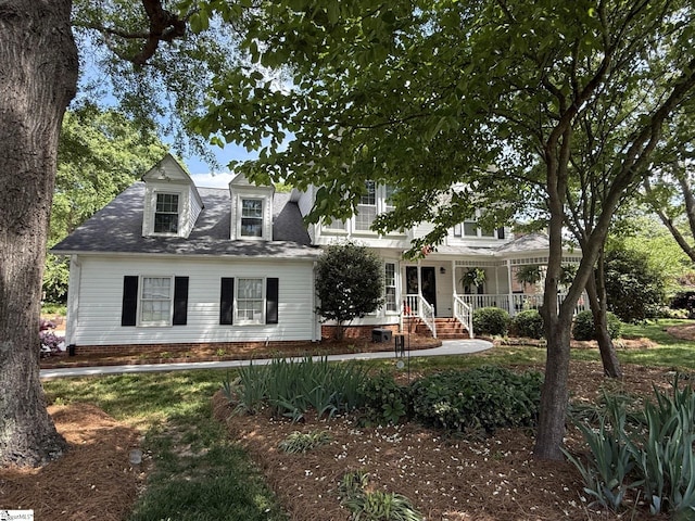 cape cod house with a porch and roof with shingles