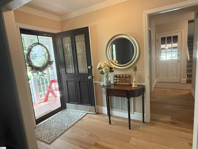 entryway with baseboards, light wood-type flooring, ornamental molding, and plenty of natural light