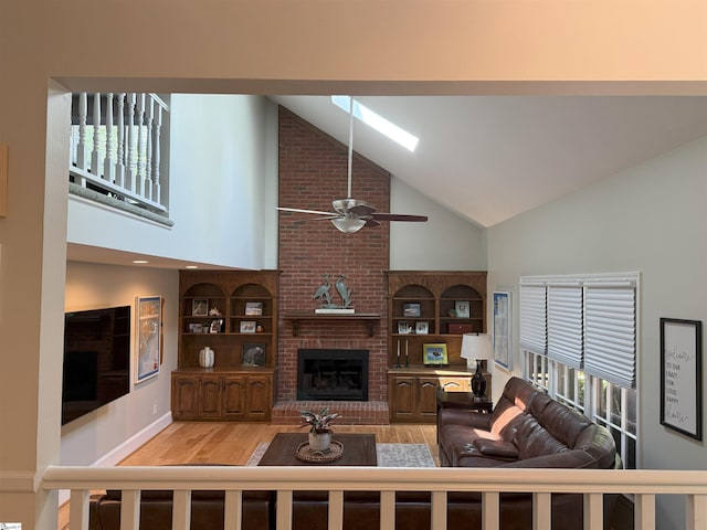 living area featuring high vaulted ceiling, ceiling fan, wood finished floors, and a fireplace