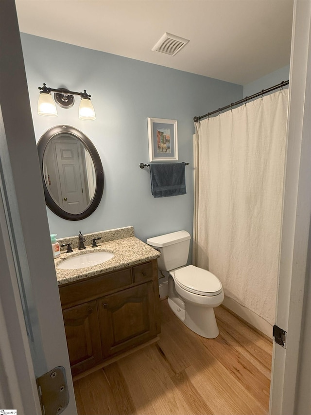 bathroom with toilet, vanity, visible vents, and wood finished floors